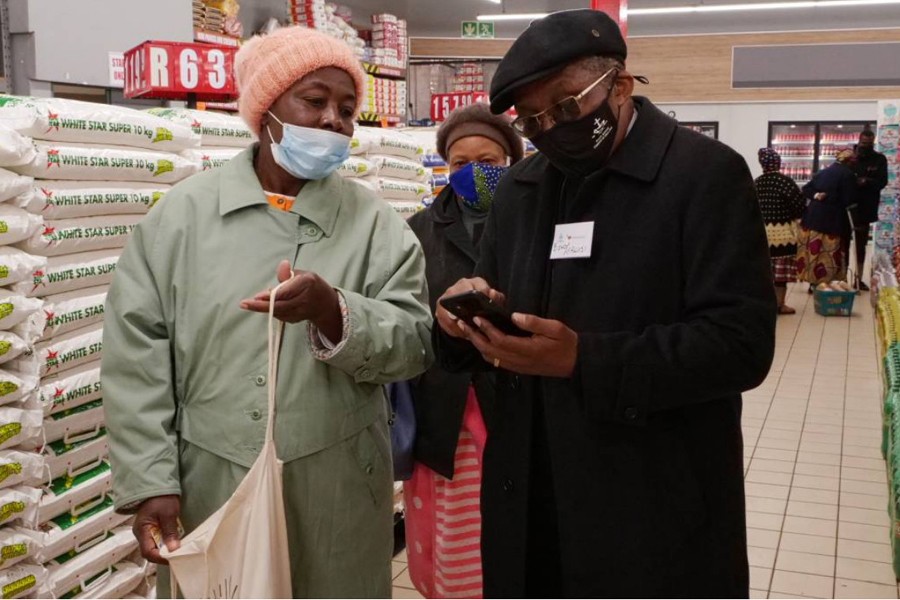 Bishop Malusi Mpumlwana, the general secretary of the South African Council of Churches, helps pensioner Phila Sheila Ngobeni register for a vaccine in Soweto, South Africa on June 3, 2021 — Thomson Reuters Foundation photo