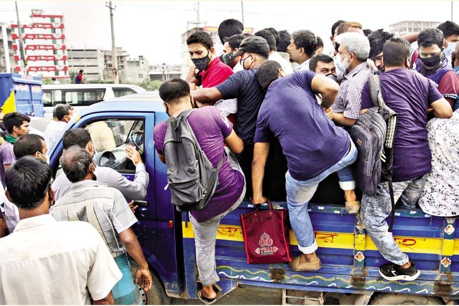 As public transport stayed off the road amid new coronavirus-induced restrictions, commuters scramble to get on a pick-up van to reach their destinations, defeating the purpose of the lockdown. The photo was taken on Dhaka-Chattogram highway in Rayerbagh area of the capital on Monday — FE photo