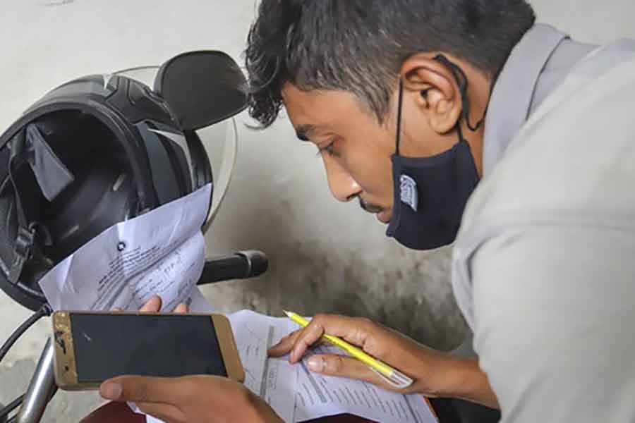 A migrant worker filling in the registration form on a motorcycle for the coronavirus vaccine at Probashi Kalyan Bhaban in Dhaka on July 2 -bdnews24.com photo