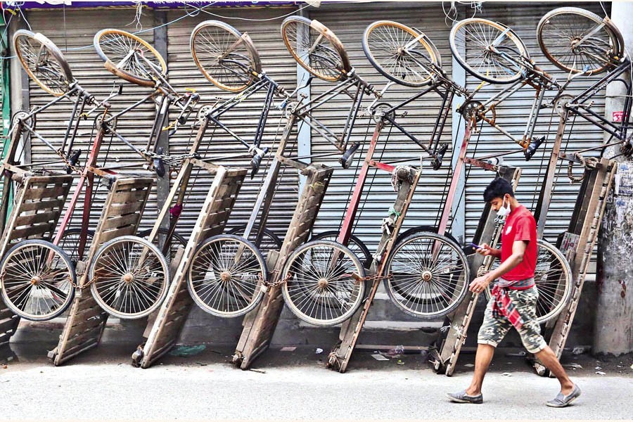 Rickshaw-vans, which are meant for carrying goods, now lying idle by the roadside in Bangshal area of the city. With shops and businesses remaining shut during the lockdown, the income of the van drivers has come down to zero. The photo was taken on Monday — FE photo by KAZ Sumon