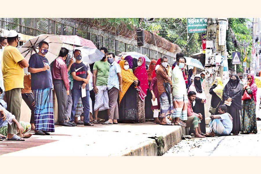 People waiting for a TCB truck to arrive in the Mugda area of the city on Monday so that they can buy daily essentials at subsidised prices. Though it was around 11:30am, the truck was yet to show up, much to their frustration. — FE photo