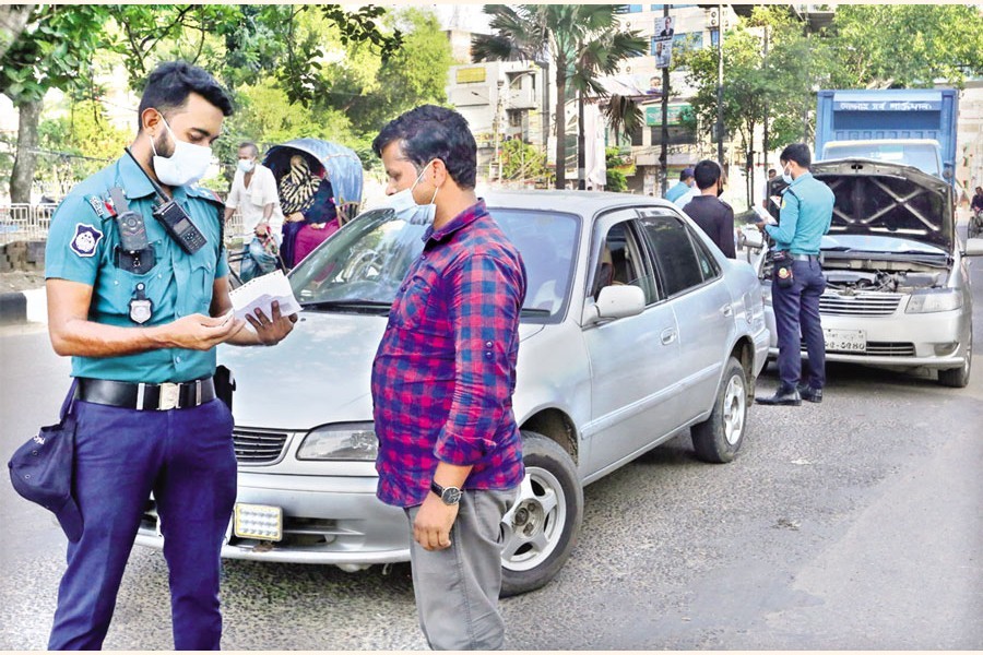 Police checking the documents of a car on the Gulistan-Paltan road in the city on Friday during the ongoing Covid-induced lockdown in force across the country. — FE photo