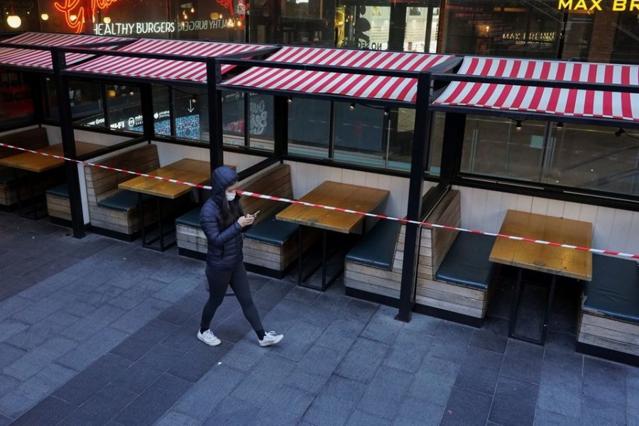 A woman wearing a protective mask walks past city centre restaurant tables closed to seating in accordance with public health regulations during a lockdown to curb the spread of the coronavirus disease (Covid-19) in Sydney, Australia on July 5, 2021 — Reuters/Files