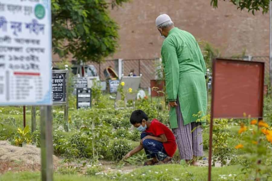 A boy cleaning the grave of his grandmother at Rayerbazar Graveyard in Dhaka after Jum’a prayers on Friday -bdnews24.com photo