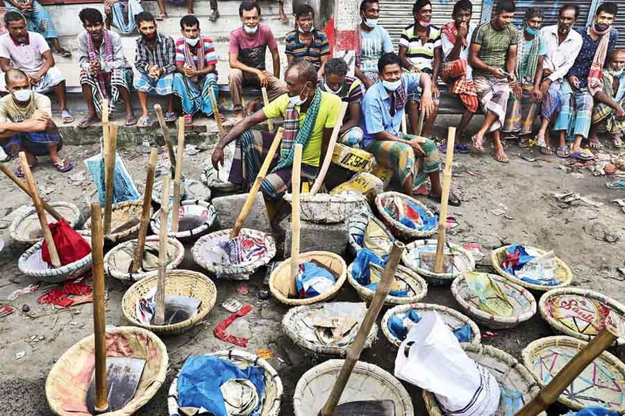 A group of day labourers waiting in vain to be hired for work at Shanir Akhra in the city on Monday as coronavirus-induced lockdown has severely impacted their livelihoods — FE photo by Shafiqul Alam