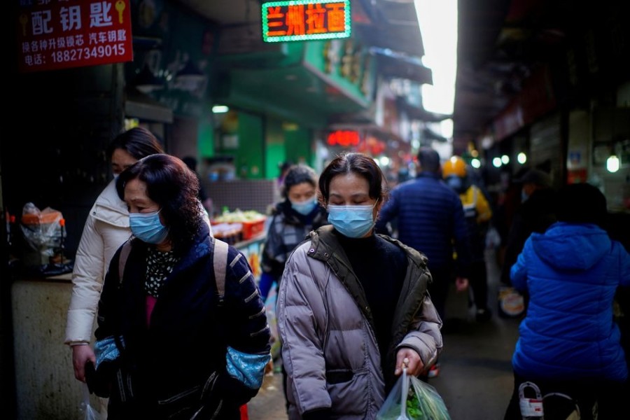 People wearing face masks walk on a street market, following an outbreak of the coronavirus disease (Covid-19) in Wuhan, Hubei province, China on February 8, 2021