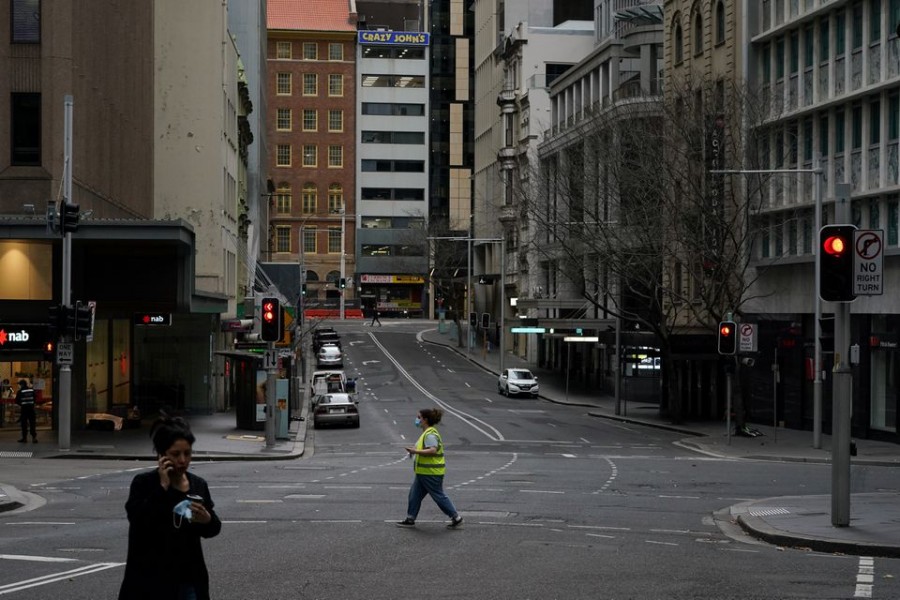 People with protective face masks walk through the quiet city centre during a lockdown to curb the spread of a coronavirus disease (COVID-19) outbreak in Sydney, Australia, July 28, 2021. REUTERS/Loren Elliott