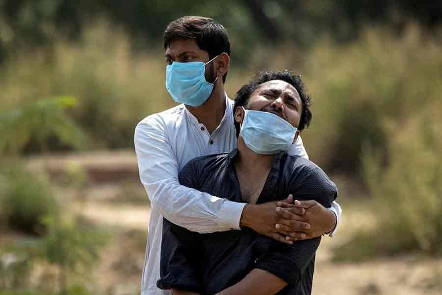 A man is consoled by his relative as he sees the body of his father, who died from complications related to the coronavirus disease (COVID-19), before his burial at a graveyard in New Delhi of India on April 16 this year -Reuters file photo