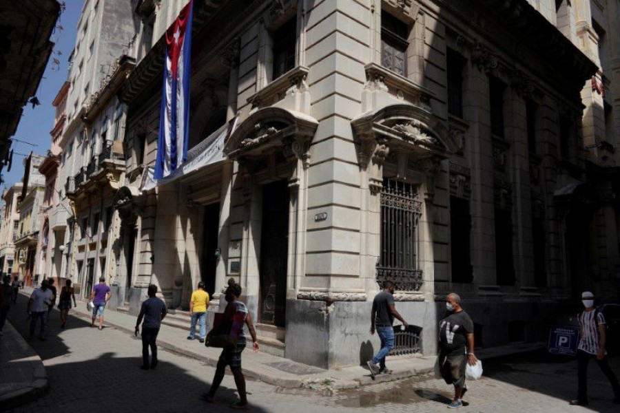 People walk under a Cuban flag at a commercial area amid concerns about the spread of the coronavirus disease (COVID-19), in Havana, Cuba, August 3, 2021 - Reuters