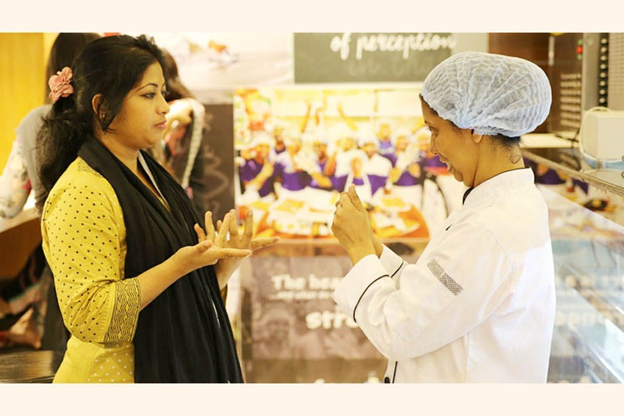 Liza (R) takes a customer's order in sign language at a restaurant in Dhaka as she can neither speak nor hear.      —ILO Photo