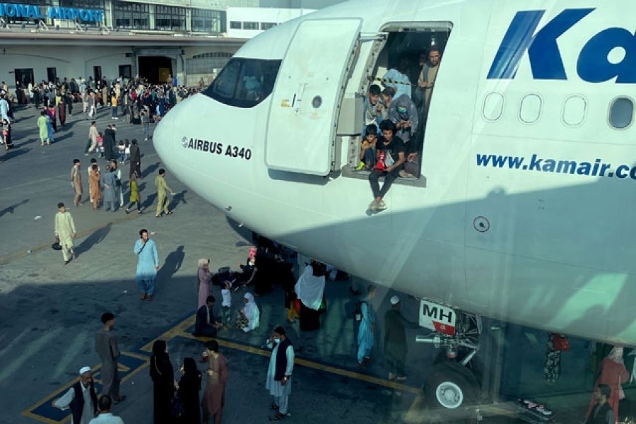 An undated amateur picture obtained by Reuters on August 19, 2021 shows people at the door of an aircraft at the airport in Kabul, Afghanistan. Picture taken through glass. Handout via Reuters