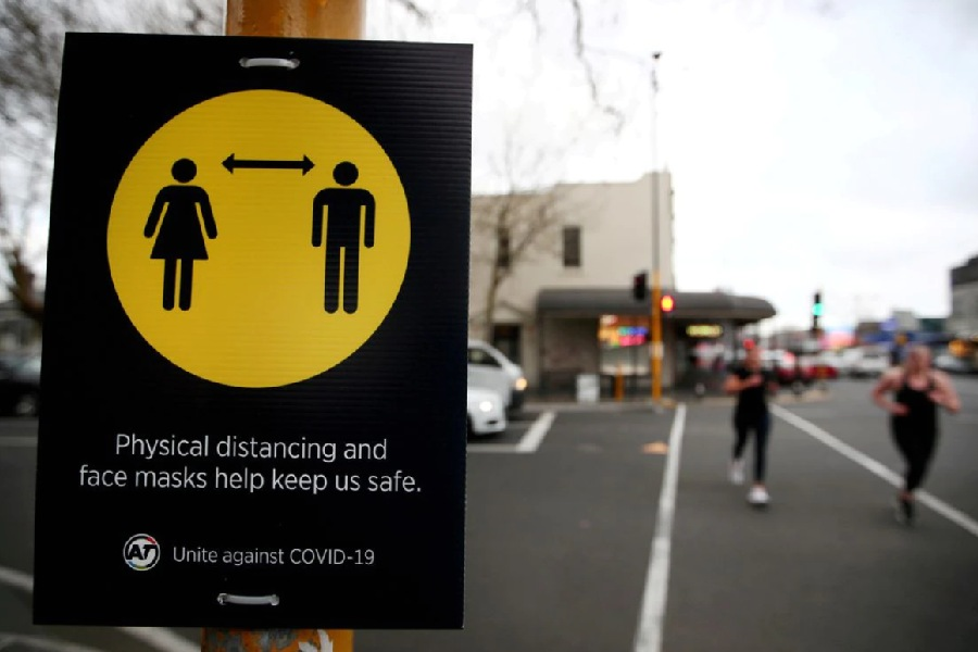 People jog past a social distancing sign on the first day of New Zealand's new coronavirus disease (COVID-19) safety measure that mandates wearing of a mask on public transport, in Auckland, New Zealand, August 31, 2020. REUTERS/Fiona Goodall/File Photo