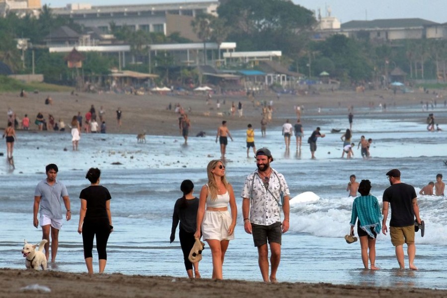 Tourists walk on a beach as the government extends restrictions to curb the spread of coronavirus disease (COVID-19) in Badung, Bali, Indonesia September 9, 2021. Antara Foto/Nyoman Hendra Wibowo/via REUTERS