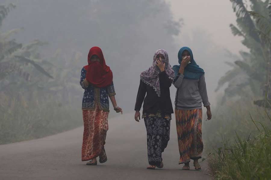 Villagers walking on a street as the haze shrouds Pulau Mentaro village in Muaro Jambi, on the Indonesian island of Sumatra, on September 15 in 2015 –Reuters file photo