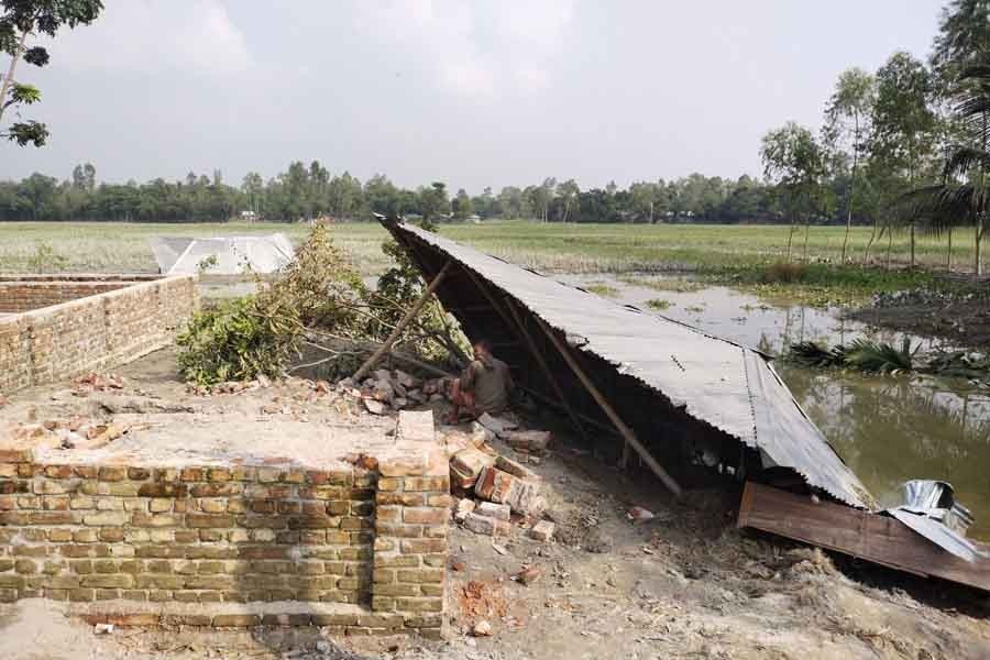 A man has taken shelter under a tin-shed roof as flood washes away his home. The photo was taken from the Mohishkhocha area of Aditmari upazila in Lalmonirhat — FE Photo