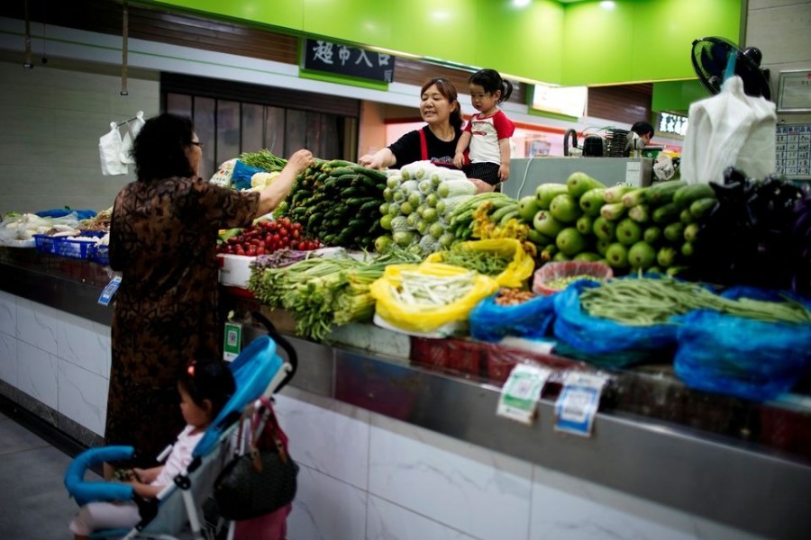 Two grandmothers with their granddaughter trade vegetables at a market on the outskirts of Shanghai, China on June 3, 2021 — Reuters/Files