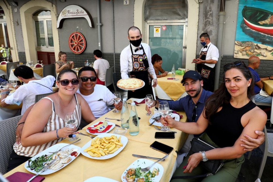 Diners at a restaurant pose for a photo with a server wearing a protective mask, as Sicily returns to being a 'yellow zone' with tighter coronavirus disease (COVID-19) restrictions, in Catania, Italy, August 30, 2021. REUTERS/Antonio Parrinello