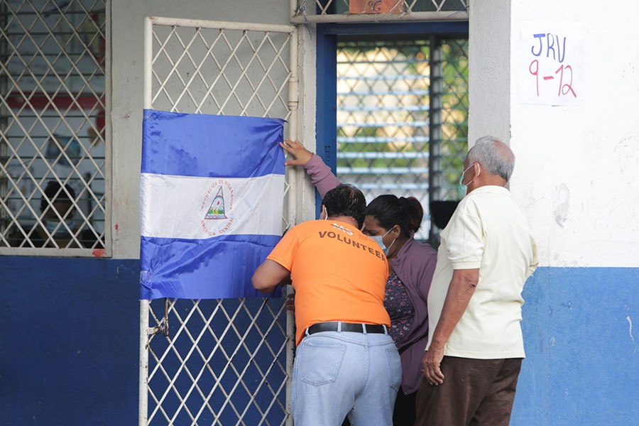 Electoral workers place a Nicaraguan flag on the door of a classroom, at a school used as polling station during the country's presidential election in Managua, Nicaragua on November 7, 2021 — Reuters photo