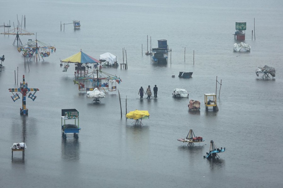 People wade through a flooded beach after heavy rainfall in Chennai, India, November 8, 2021. REUTERS/P. Ravikumar