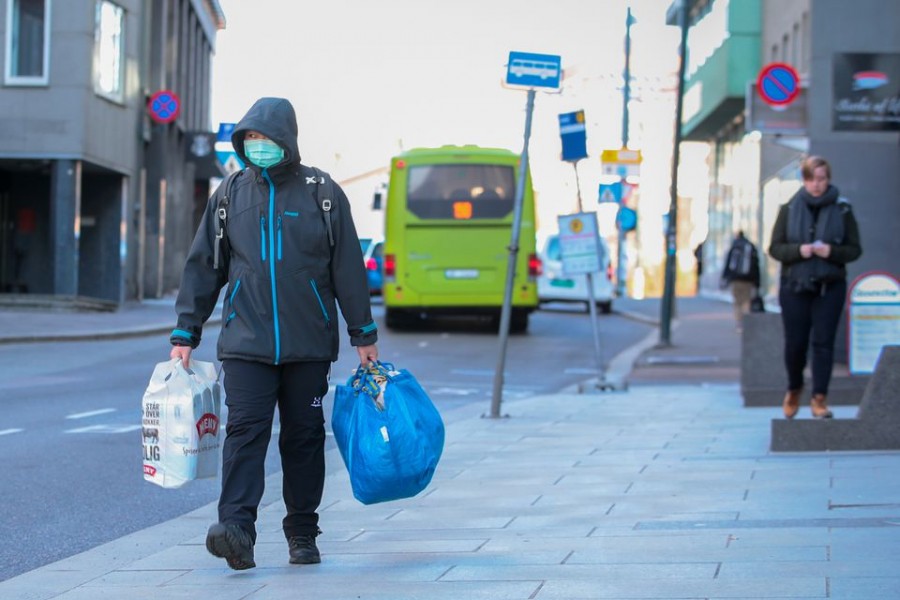 A man wearing a protective mask carries shopping bags as he walks on the streets of Oslo following an outbreak of the coronavirus disease (COVID-19), in Oslo, Norway March 13, 2020. NTB Scanpix/Hakon Mosvold Larsen via REUTERS/File Photo