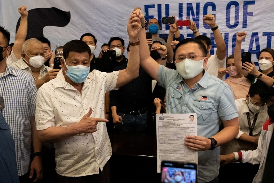 Philippine President Rodrigo Duterte raises the hand of Philippine Senator Christopher "Bong" Go after filing his certificate of candidacy for president for the 2022 national election, at the Commission on Elections, in Manila, Philippines, November 13, 2021. REUTERS/Lisa Marie David/File Photo