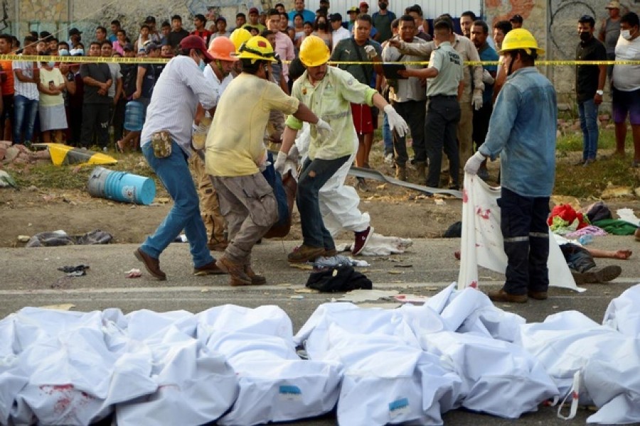 Men carry a body at the site of a trailer accident that left at least 49 people dead, most of them migrants from Central America, in Tuxtla Gutierrez, in Chiapas state, Mexico December 9, 2021 – Reuters