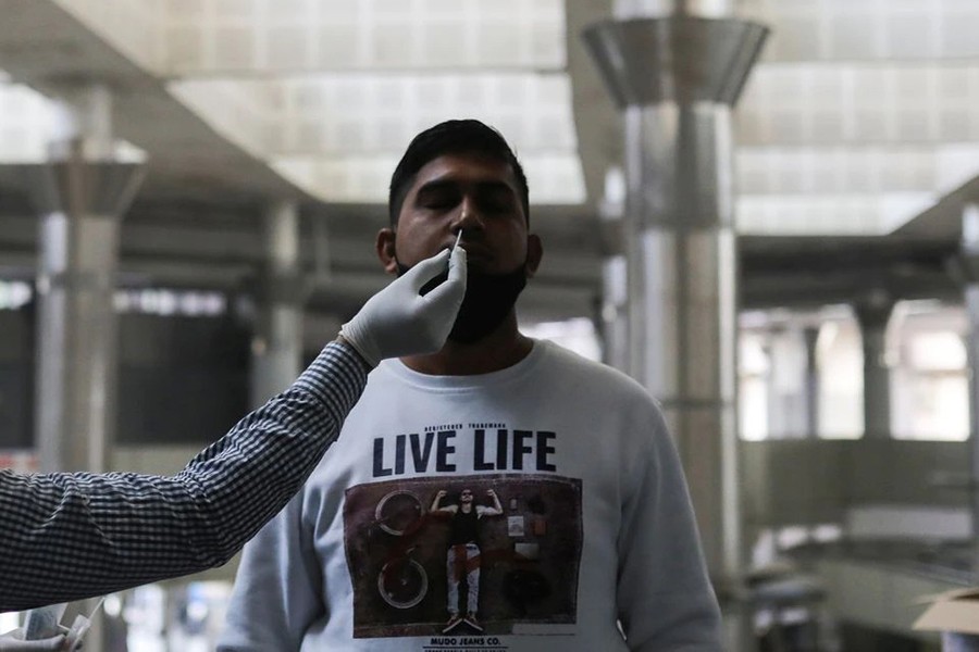 A healthcare worker collects a coronavirus disease (Covid-19) test swab sample from a man at a bus terminal in New Delhi, India on December 6, 2021 — Reuters/Files