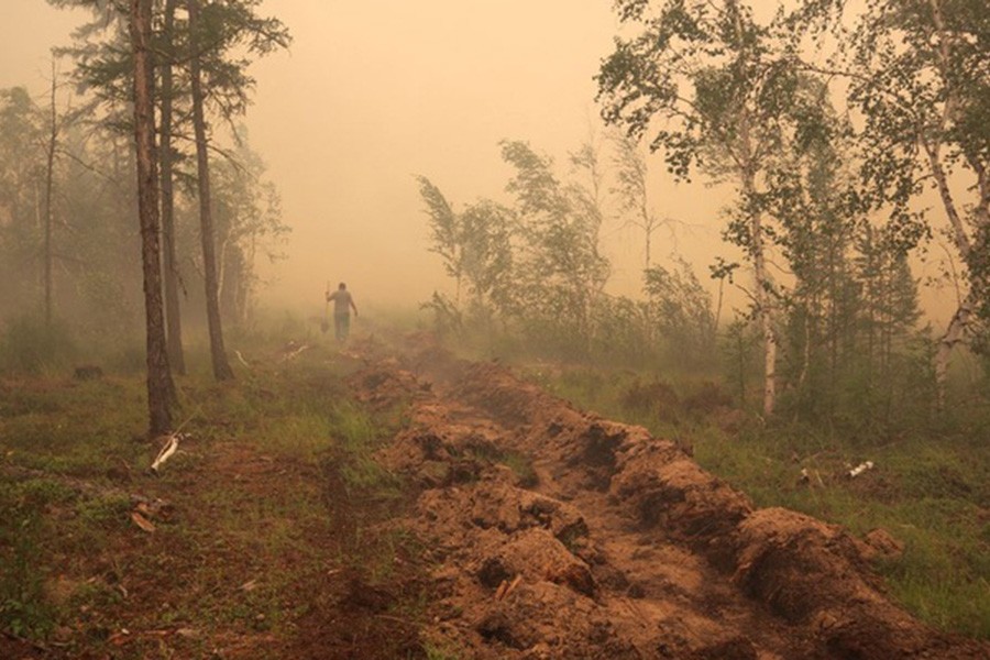 A man digs a control line during the work on extinguishing a forest fire near the village of Magaras in the region of Yakutia, Russia Jul 17, 2021. REUTERS