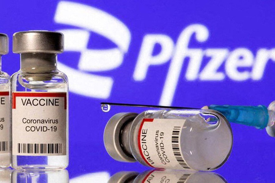 Vials labelled "VACCINE Coronavirus COVID-19" and a syringe are seen in front of a displayed Pfizer logo in this illustration taken December 11, 2021. REUTERS/Dado Ruvic/Illustration