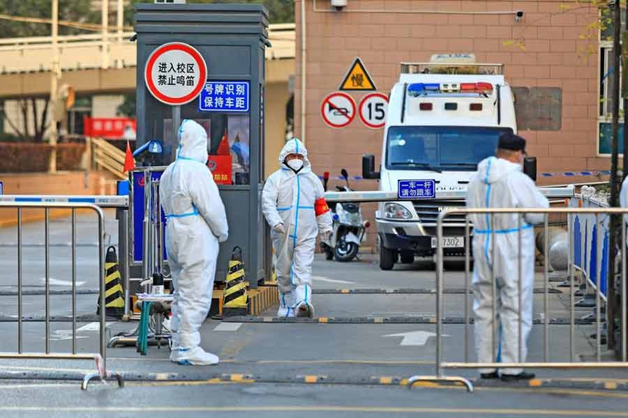 Workers in protective suits standing at an entrance to a university's residential area under lockdown in Xian in Shaanxi province of China on December 20 this year following the coronavirus disease (COVID-19) outbreak  -Reuters file photo