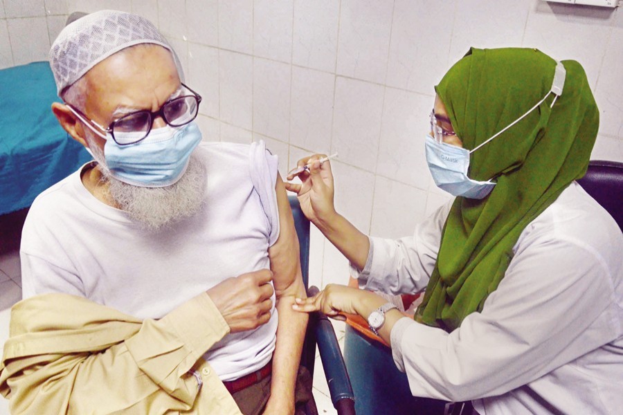 A health worker administering a booster dose of a Covid-19 vaccine to an elderly man at Dhaka Medical College Hospital on Saturday - Focus Bangla