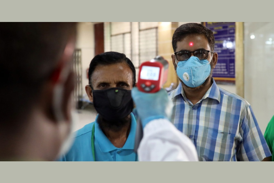 A security personnel checks the body temperature of customers in Dhaka, Bangladesh, 2 April 2020 - REUTERS/Mohammad Ponir Hossain