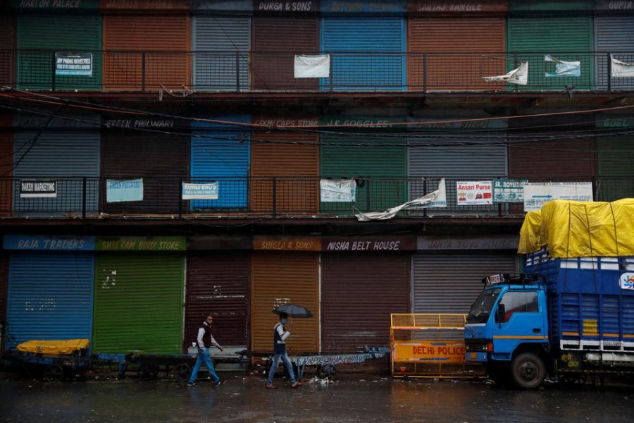 People walk past closed shops at a market area after authorities in the capital ordered a weekend curfew, following the rise in the coronavirus disease (COVID-19) cases, in the old quarters of Delhi, India, January 8, 2022. REUTERS/Adnan Abidi