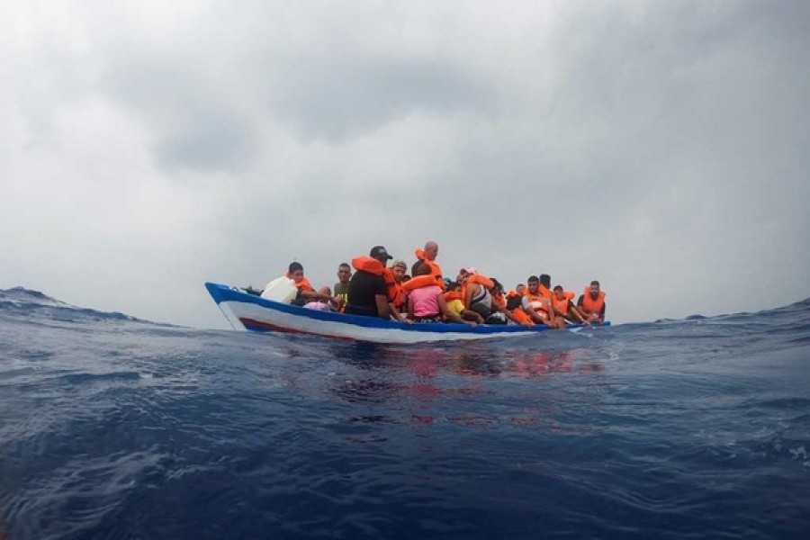 Migrants on a wooden boat wait for the Italian Guardia Costiera near the island of Lampedusa, in the Mediterranean Sea, September 1, 2021. Reuters