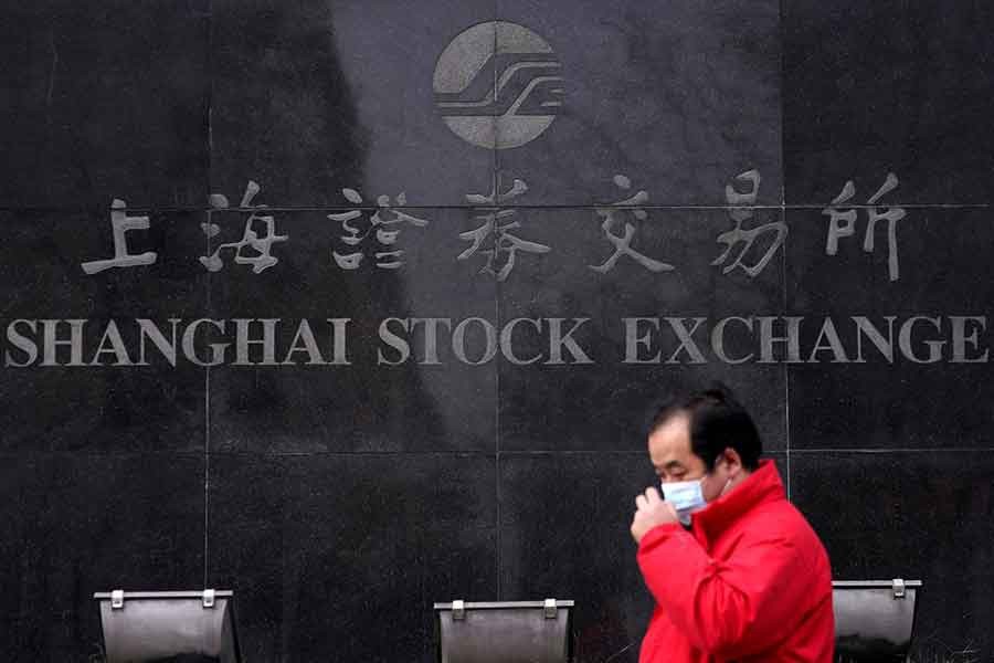 A man wearing a mask walks at the Shanghai Stock Exchange building at the Pudong financial district in Shanghai, China, as the country is hit by an outbreak of a new coronavirus, February 3, 2020 – Reuters/Aly Song