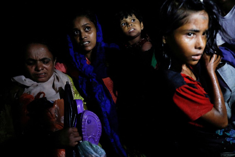 Women carry children through the water as hundreds of Rohingya refugees arrive under the cover of darkness by wooden boats from Myanmar to the shore of Shah Porir Dwip, in Teknaf, near Cox's Bazar in Bangladesh on September 27, 2017 — Reuters/Files