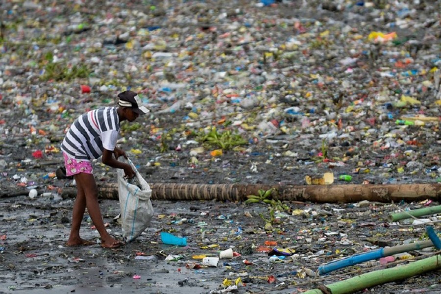 A woman picks up plastic cups along the riverbank of Pasig river, in Manila, Philippines, June 10, 2021 — Reuters/Lisa Marie David