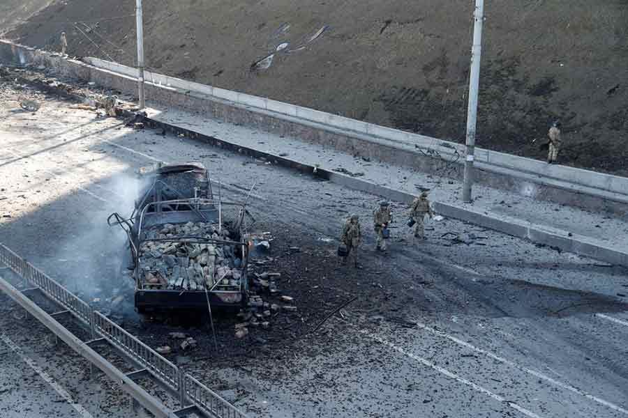 Ukrainian servicemen walking by a damaged vehicle, at the site of fighting with Russian troops in Kyiv on Saturday after Russia launched a massive military operation against Ukraine –Reuters photo