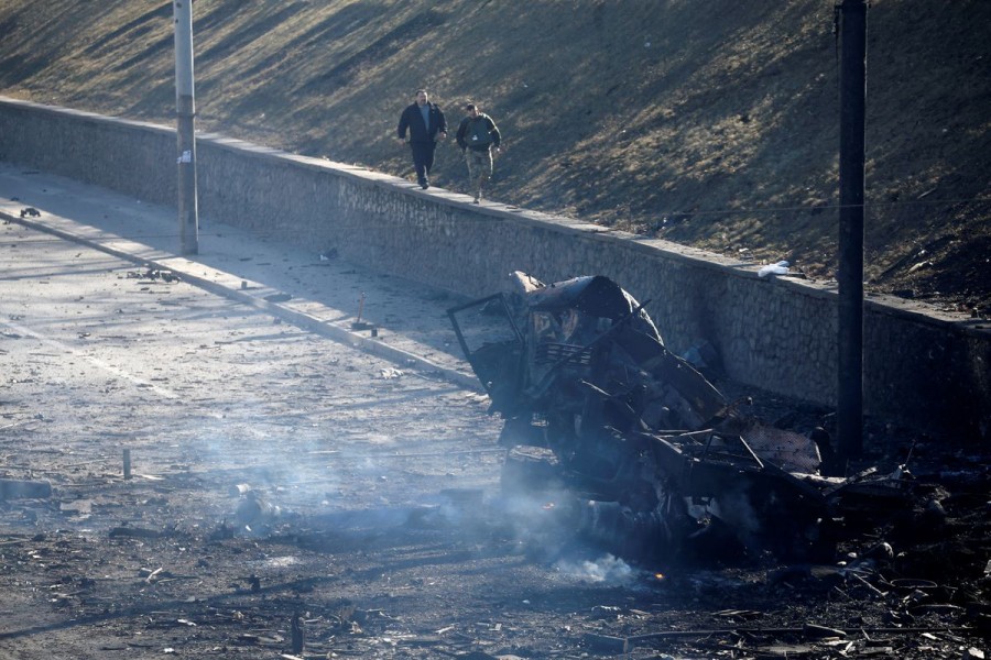 People walk towards a damaged vehicle, at the site of fighting with Russian troops, after Russia launched a massive military operation against Ukraine, in Kyiv, Ukraine February 26, 2022. REUTERS/Valentyn Ogirenko