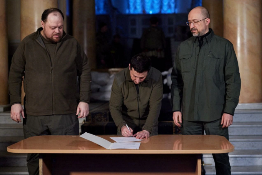 Ukrainian President Volodymyr Zelenskiy signs an official request for Ukraine to join the European Union, with Prime Minister Denys Shmygal (R) and Parliament Speaker Ruslan Stefanchuk standing next to him, in Kyiv, Ukraine, February 28, 2022. Ukrainian Presidential Press Service/Handout via REUTERS