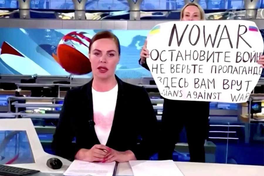 A person interrupts a live news bulletin on Russia's state TV "Channel One" holding up a sign that reads "NO WAR. Stop the war. Don't believe propaganda. They are lying to you here." at an unknown location in Russia March 14, 2022, in this still image obtained from a video uploaded on March 14. Channel One/via REUTERS