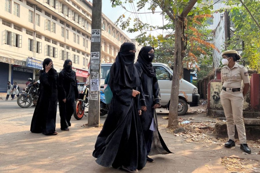 Hijab-wearing students arrive to attend classes as a policewoman stands guard outside a government girls school after the recent hijab ban, in Udupi town in the southern state of Karnataka, India, February 16, 2022. REUTERS/Sunil Kataria