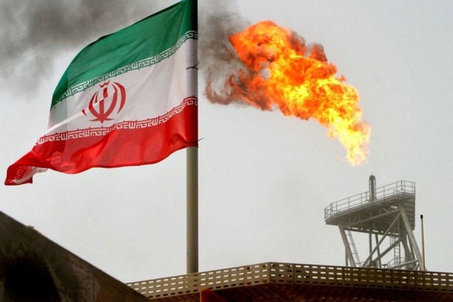 A gas flare on an oil production platform is seen alongside an Iranian flag in the Gulf July 25, 2005. REUTERS/Raheb Homavandi