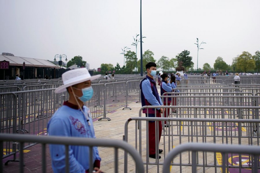 Staff members wearing face masks stand outside the Shanghai Disneyland theme park as it reopens following a shutdown due to the coronavirus disease (COVID-19) outbreak, at Shanghai Disney Resort in Shanghai, China May 11, 2020. REUTERS/Aly Song