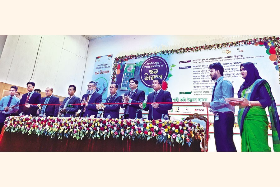 Financial Institutions Division Secretary Sheikh Mohammad Salim Ullah along with RAKUB officials and other guests inaugurates the mobile app and internet banking of RAKUB by cutting a ribbon as the chief guest at a function held at Zila Parishad auditorium in Rajshahi on Wednesday