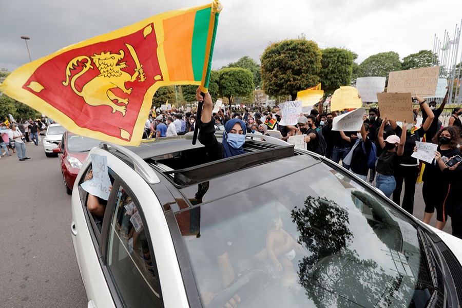 A woman waves a Sri Lankan flag from inside a car as people shout slogans against Sri Lanka's President Gotabaya Rajapaksa and demand that Rajapaksa family politicians step down, during a protest amid the country's economic crisis, on a main road in Colombo, Sri Lanka on April 4, 2022 — Reuters photo