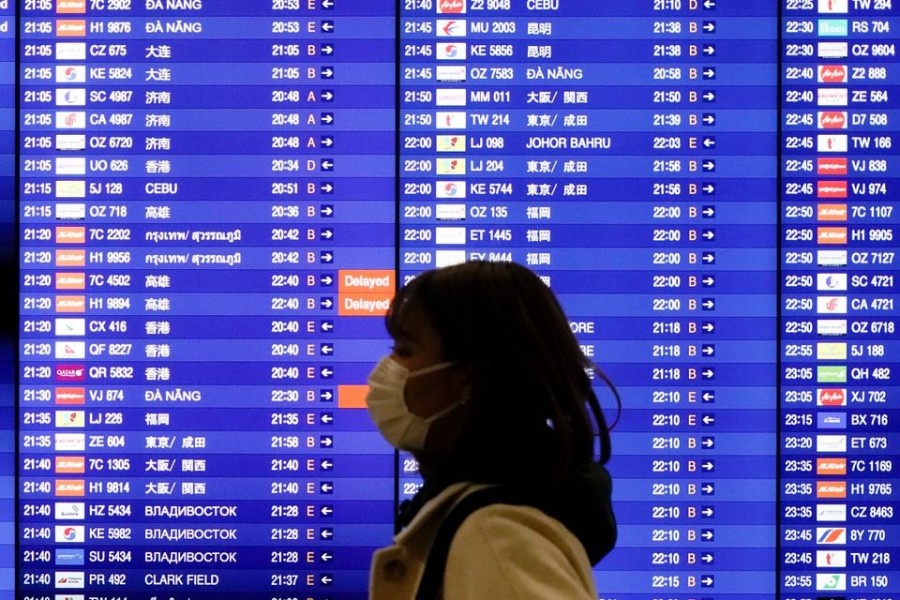 A woman wearing a mask to prevent contracting coronavirus walks past an electronic board showing flight schedules at Incheon International Airport in Incheon, South Korea, January 3, 2020. REUTERS/Kim Hong-Ji