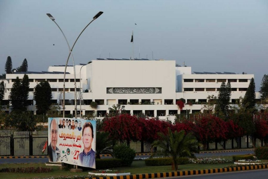 A campaign poster featuring Pakistani Prime Minister Imran Khan is seen with the parliament building in the background, in Islamabad, Pakistan Apr 2, 2022 — Reuters