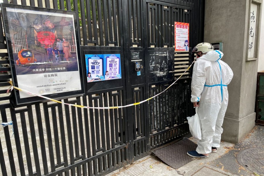 A delivery courier in a protective suit delivers goods at a locked down residential compound, amid the coronavirus disease (COVID-19) outbreak, during the Labour Day holiday in Shanghai, China April 30, 2022. REUTERS/Brenda Goh