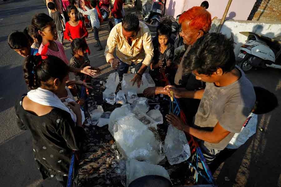 A man breaking a block of ice to distribute it among the residents of a slum during hot weather in Ahmedabad of India on April 28 this year –Reuters file photo